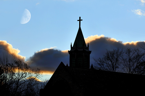 Silhouette of a Christian cross with sunset light in the background symbolizing faith and religion or resurrection of Jesus Christ