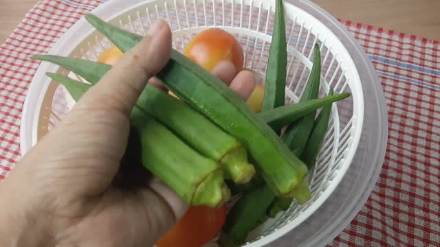 Hand Checking Fresh Okra Before Cooking