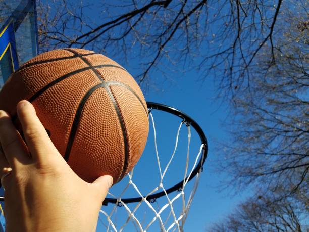 istock hand dunking a basketball with hoop and trees 1288760311