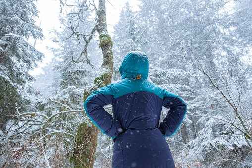 Woman stopping to watch snow falling at Parkgate Park, North Vancouver, British Columbia, Canada
