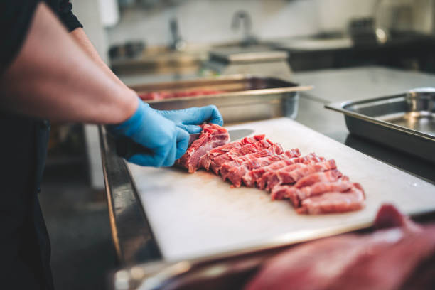 istock Male butcher cut raw meat with sharp knife in restaurants kitchen 1288773006