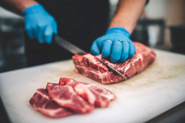 istock Male butcher cut raw meat with sharp knife in restaurants kitchen 1288773059