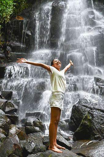 Young smiling asian woman with arms outstretched in front of waterfall, Nikon Z7