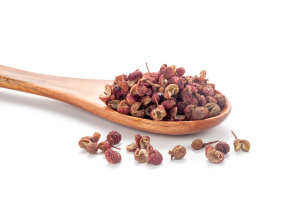 sichuan pepper (zanthoxylum bungeanum) in a wooden spoon sichuan pepper (zanthoxylum bungeanum) in a wooden spoon isolated on white background. Chinese prickly ash. sichuan province stock pictures, royalty-free photos & images