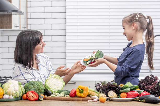 mãe e filha felizes estão preparando salada de legumes. conceito de comida saudável. - mother green sparse contemporary - fotografias e filmes do acervo