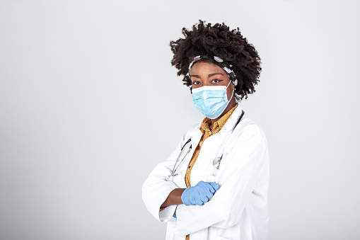 African american female doctor wear white medical coat stethoscope face mask look at camera closeup headshot portrait. Brave proud black hero physician on grey, healthcare safety, medicine protection