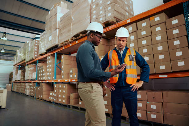 portrait of a male worker and manger together checking the stock using digital tablet at large storehouse - male african descent africa ethnic imagens e fotografias de stock