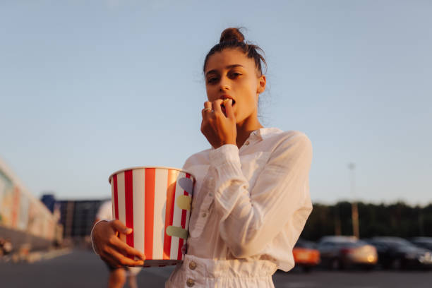 Young cute woman holding popcorn in a shopping mall parking lot stock photo
