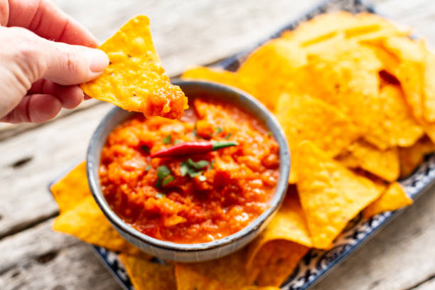 istock Hand holding a nacho with salsa sauce 1288780017