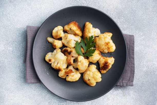 istock Fried cauliflower florets in batter on a black plate. Grey concrete background. Copy space. 1288782581