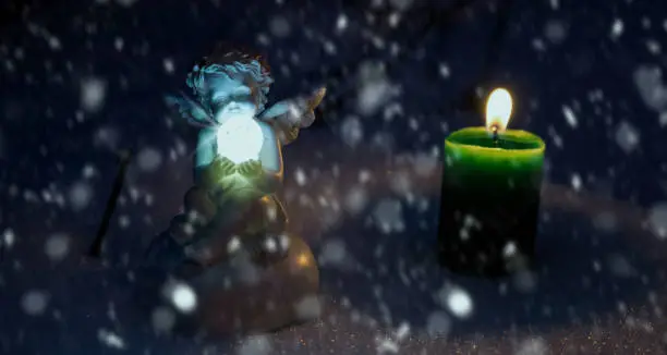 Photo of Angel (figurine) and a green candle on the snow.