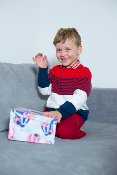 istock Cheerful boy sitting on bed with a big gift. 1288797366