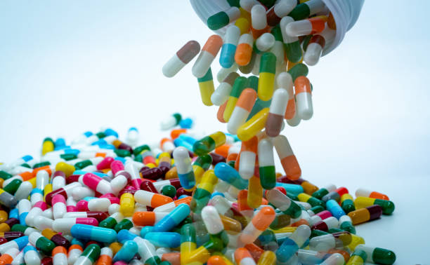 プラスチック製の薬物ボトルから多色のカプセル剤を注ぐ。抗生物質薬の過剰使用概念。抗生物質薬剤耐性.製薬業界。薬局ドラッグストア製品。薬の副作用. - amoxicillin ストックフォトと画像