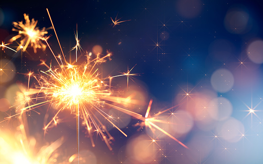 Glittering sparkler against bokeh light background with copy space