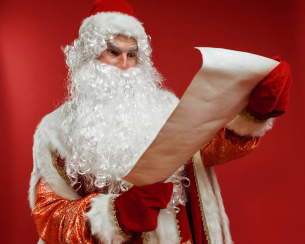 istock Santa Claus unfolds an ancient scroll and reads the text on it in surprise 1288801122