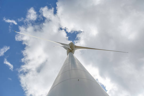 Bottom-up view of a wind turbine, sky with clouds as background...