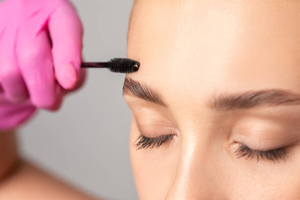 istock Makeup artist combs eyebrows with a brush after dyeing in a beauty salon.Professional makeup and cosmetology skin care. 1288804370
