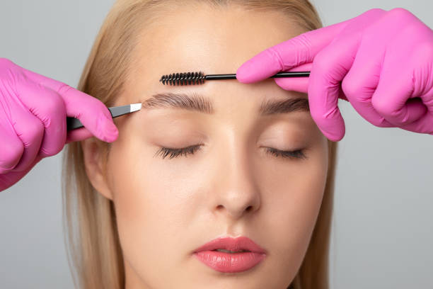 istock Makeup artist combs  and plucks eyebrows after dyeing in a beauty salon.Professional makeup and cosmetology skin care. 1288804441