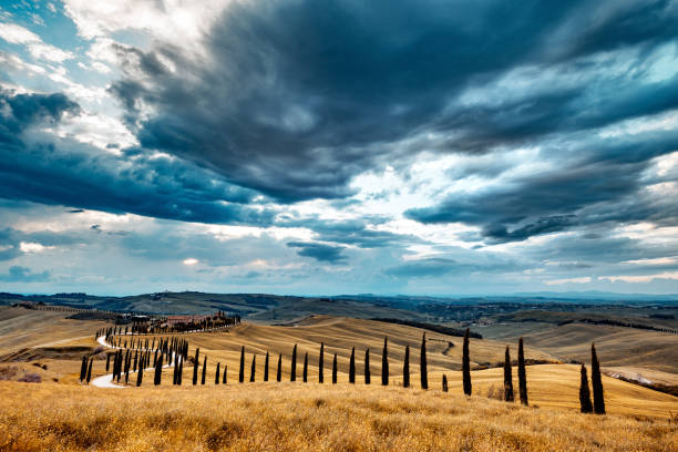 tuscany landscape at sunset - crete senesi - winding road sunlight field cultivated land imagens e fotografias de stock