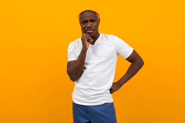 istock thinking african black man in a white t-shirt posing on a yellow background 1288805533