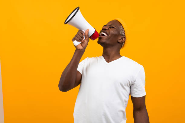 istock black african man speaks in megaphone on isolated orange background 1288805562