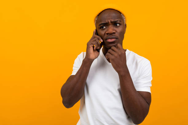 istock handsome pensive serious american man talking on the phone on a yellow studio background 1288805802