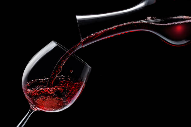 rotwein wird in ein weinglas auf schwarzem grund gegossen. - decanter wine wineglass red wine stock-fotos und bilder