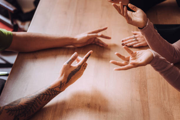 High angle view of friends hands gesturing while discussing over table in cafe