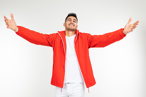 smiling man in a sports red suit holds out a helping hand on a white background with copy space.