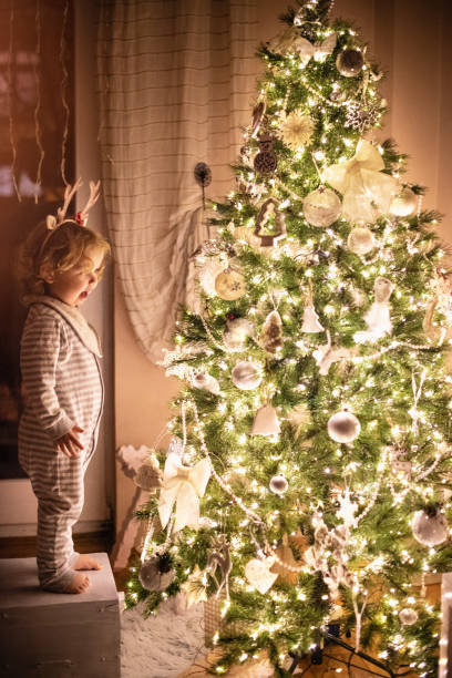 istock Child amazed by a beautifully lit Christmas tree on a Christmas eve 1288808022