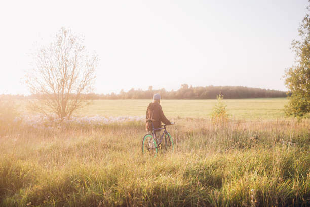 Young woman crossing the meadow with her bike. She's going to pick some wild flowers.