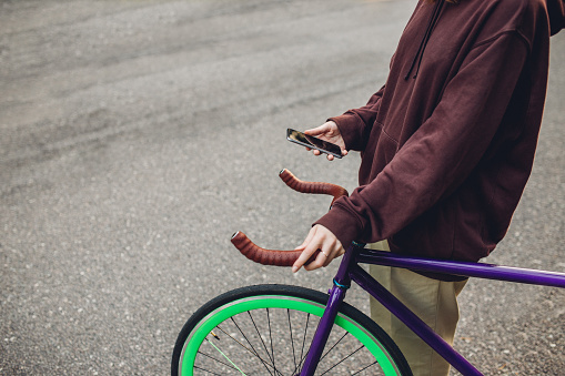 Hands using smartphone next to bicycle