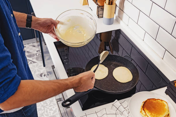 istock Man frying pancakes on the pan at his kitchen. 1288808955