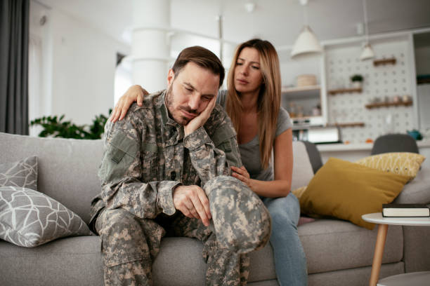 istock Depressed soldier sitting on sofa in living room 1288808970