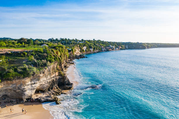 Beach scene from above - blue ocean waves hitting a sandy beach.