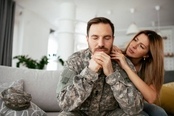 soldato depresso seduto sul divano in soggiorno - men male military beautiful foto e immagini stock
