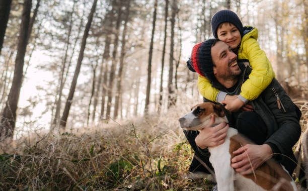 Photo of young father and his son, having a walk with their family dog, on a cold, but sunny winter day
