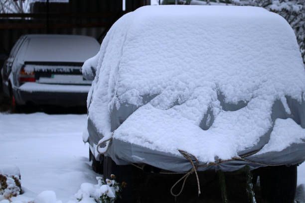 istock A car with a protective cover. Car covered by snow. 1288811600