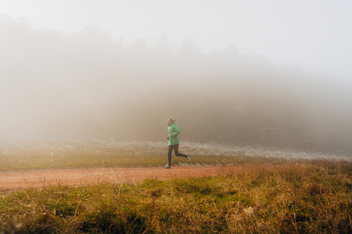 Photo of a young man running on a cold, foggy morning
