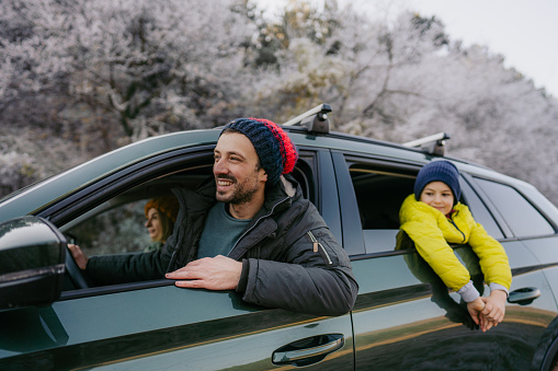 Photo of a young boy and his parents in the car on the winter road trip