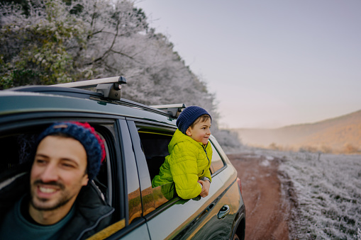 Photo of a young boy and his father in the car on the winter road trip