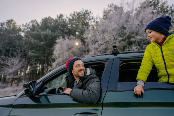 Photo of a young boy and his father in the car on the winter road trip
