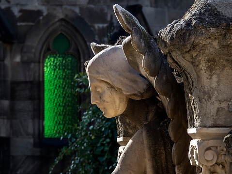 Barcelona, Spain - December 24, 2019: Angel head with green window in the background in the Poblenou Cemetery in Barcelona.