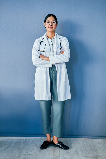 Studio portrait of a confident young doctor standing against a blue background