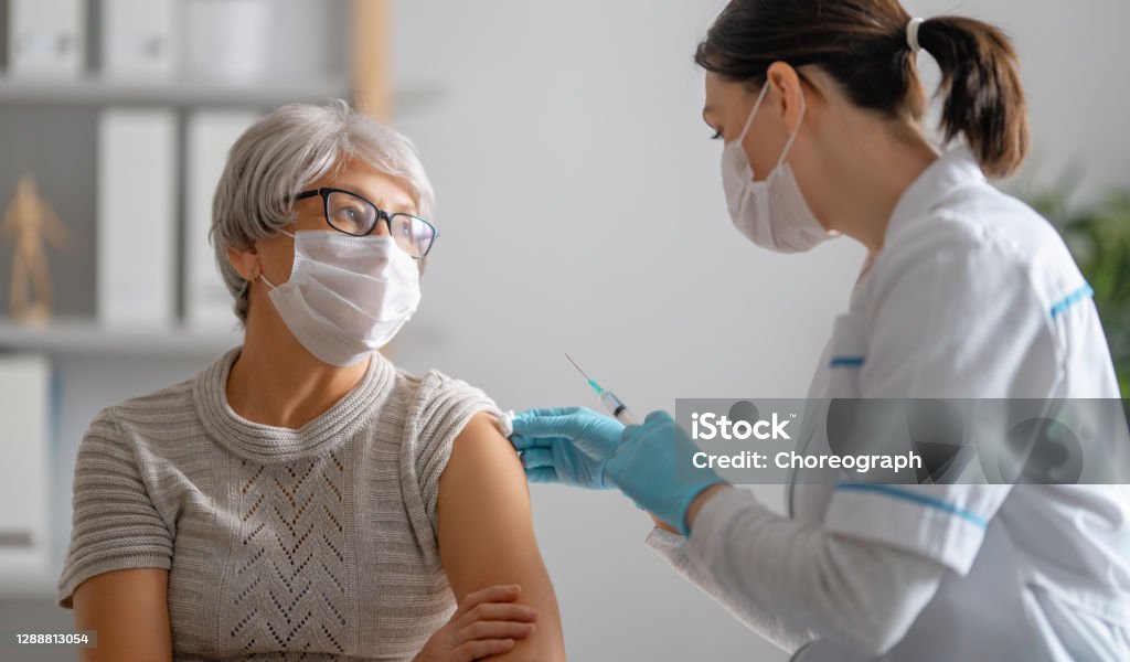 Doctor giving a senior woman a vaccination Doctor giving a senior woman a vaccination. Virus protection. COVID-2019. Vaccination Stock Photo
