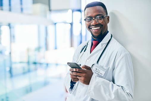Shot of a young doctor using a smartphone in a modern hospital