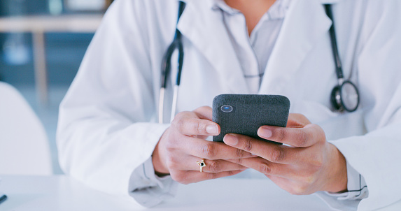 Shot of a doctor using a smartphone in a modern hospital