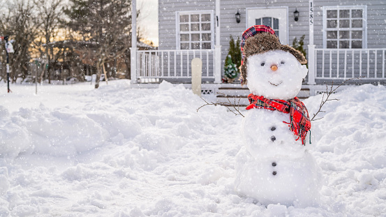 Smiling snowman in front of the house on winter day