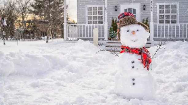 Photo of Smiling snowman in front of the house on winter day