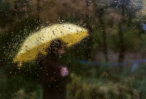 Young woman walking in rain holding a colorful umbrella